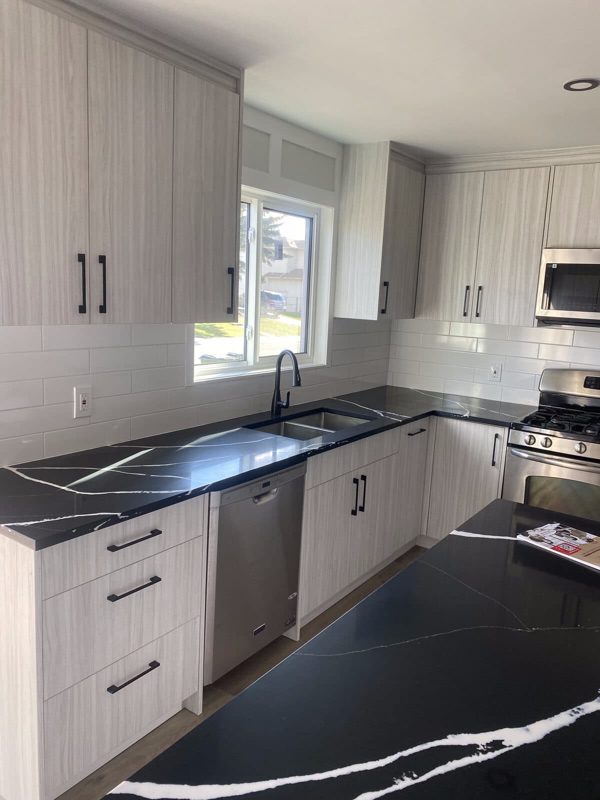 Open-concept kitchen with island and black quartz counters — JFK Surfaces renovation in Central Alberta